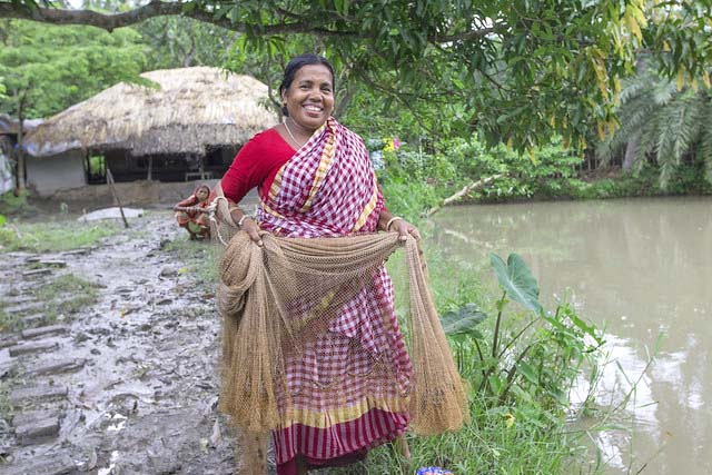 Woman harvesting shrimp from her pond in Khulna